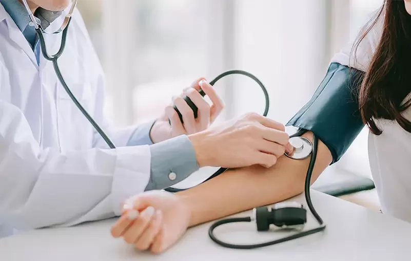Un cardiólogo mide la presión arterial de un paciente para diagnosticar presión arterial alta. 